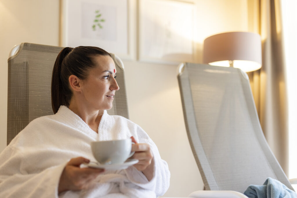 Frau im Wellnessbereich geniesst Tee und Ausblick